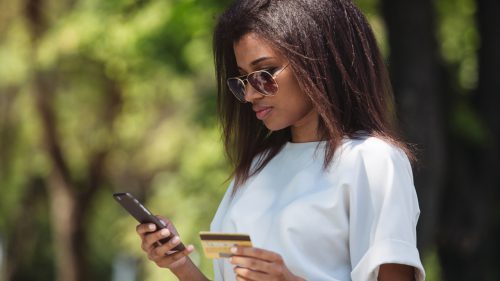 Woman holding a credit card and using cell phone for online shopping