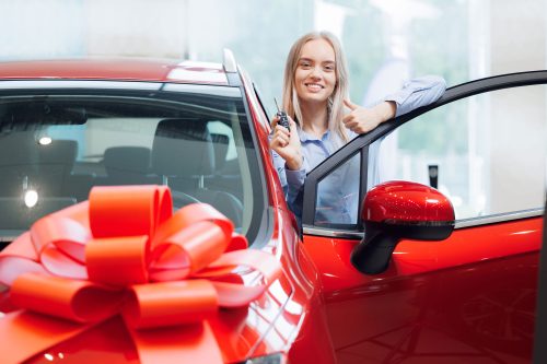 Woman smiling and confidently holding the key to her new car