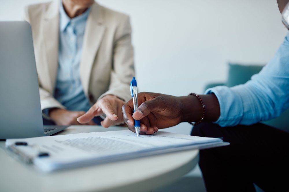 Close-up of man signing contract with insurance agent in the office