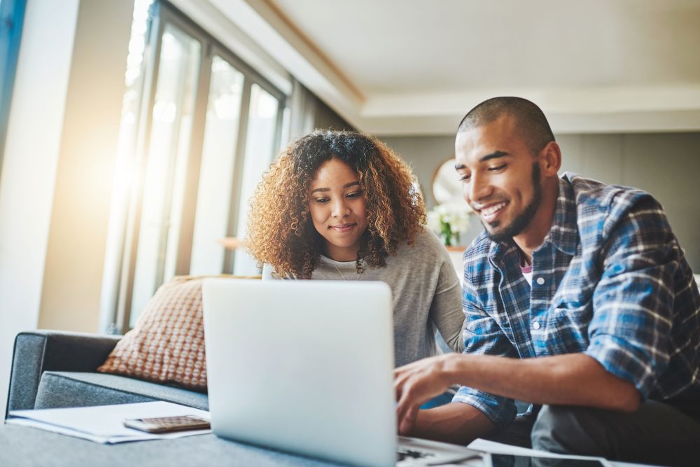 Managing money matters with wireless technology. Shot of a young couple using a laptop while working on their home finances.
