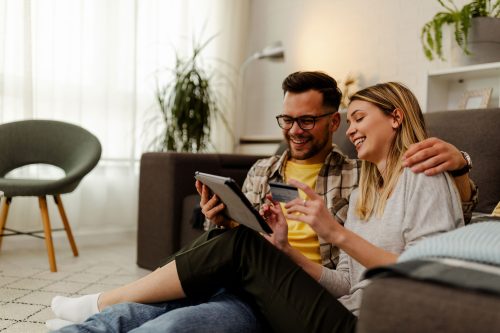 Sitting on the floor and using tablet for online shopping. Woman holding credit card.