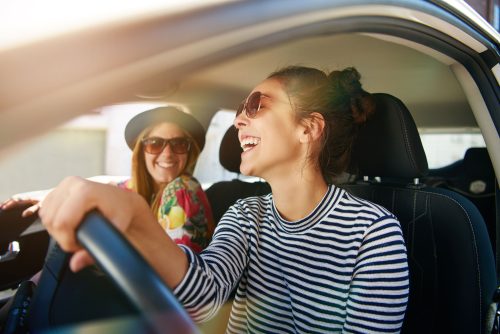 Two laughing young friends driving on a road trip together